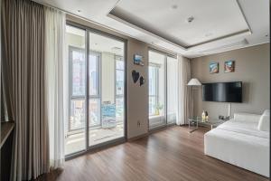 1 dormitorio con ventanas grandes, 1 cama y TV en Family Hotel & Arbol en Busan