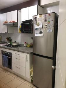 a kitchen with a stainless steel refrigerator with many magnets at Arriendo dpto o pieza por noche in San Pedro de la Paz