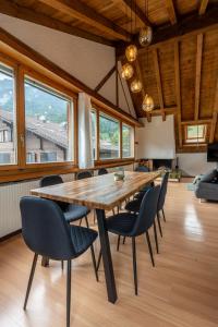 - une grande table et des chaises en bois dans une chambre avec fenêtres dans l'établissement Jungfrau-View Apartment, terrace & free parking, à Wilderswil