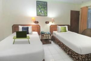 a hotel room with two beds and a laptop on a table at Urbanview Hotel Bahtera Tarakan by RedDoorz in Sibengkok