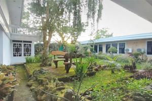 a garden in front of a house with a bench at Urbanview Hotel Bahtera Tarakan by RedDoorz in Sibengkok