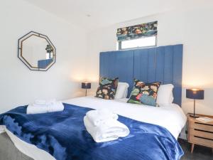 a bedroom with a large bed with a blue headboard at Bluebell Cabin in Penrith