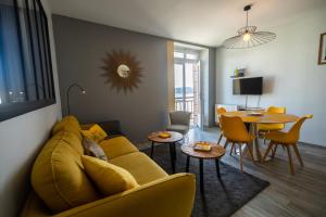 salon z żółtą kanapą i stołem w obiekcie Appartement - Le Soleil des Flots - Vue sur Mer w mieście Crozon