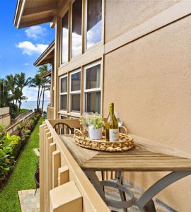 a table with a bottle of wine and flowers on a balcony at Kihei Sands B2 in Kihei +29 photos