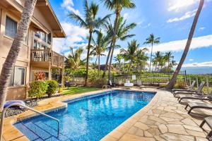 a swimming pool in front of a house with palm trees at Kihei Sands B2 in Kihei