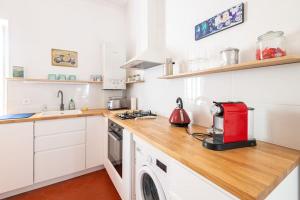 a kitchen with white cabinets and a red appliance on a counter at Le petit marin, clim/wifi/quartier gare-arènes. in Nîmes