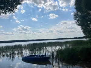 a blue boat sitting in the middle of a lake at Nowoczesny dom nad jeziorem Zarybinek-Mazury Rybno, z własnym dostępem do linii brzegowej oraz łódką in Rybno