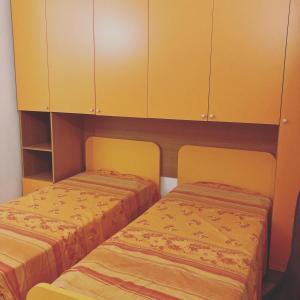two beds in a room with yellow cabinets at The Romantic House in Portoferraio