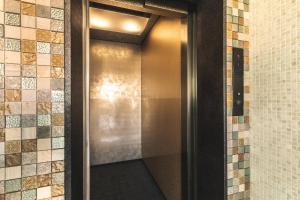 a metal elevator door in a bathroom with tiles at ルグランみしま in Hamamatsu