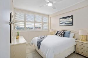 a bedroom with a white bed and a window at Sunset Sanctuary Glenelg Sth in Glenelg