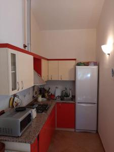 a kitchen with red cabinets and a white refrigerator at Il mare cristallino dell'Ogliastra- Marina di Tertenia in Tertenìa