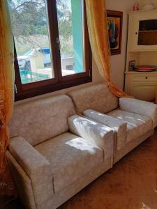 a couch in a living room with a window at Il mare cristallino dell'Ogliastra- Marina di Tertenia in Tertenìa