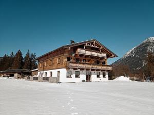 a large wooden building sitting on top of snow at Ferienwohnung Hinterwinkl in Achenkirch