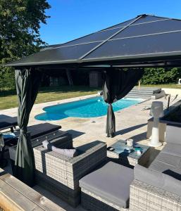 ein schwarzer Regenschirm auf einer Terrasse neben einem Pool in der Unterkunft Manoir de la Vente de Rouville in Mesnil-Raoul
