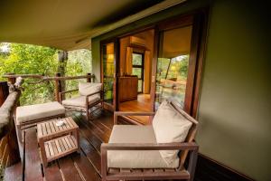a screened in porch with chairs and a table at Kapama Buffalo Camp in Kapama Private Game Reserve