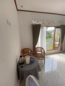 ein Esszimmer mit einem Tisch, Stühlen und einem Fenster in der Unterkunft Sri Sedana Homestay in Sidemen