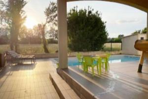 un patio con mesa y sillas junto a una piscina en Villa entière. Alpilles Aix Marseille Avignon., en Istres