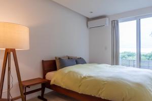 a bedroom with a bed and a lamp and a window at Yugawara Vacation House in Yugawara