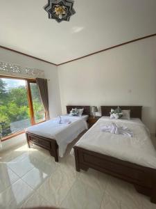 1 Schlafzimmer mit 2 Betten und einem großen Fenster in der Unterkunft Sri Sedana Homestay in Sidemen