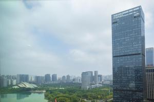 un edificio alto de cristal en una ciudad con un río en Somerset Swan Lake Hefei, en Hefei