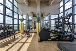 een fitnessruimte met loopbanden en gewichten in een kamer met ramen bij U Parkhotel in Enschede