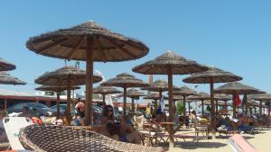 un groupe de personnes assis sous des parasols sur une plage dans l'établissement VILLA AVATOS - Near to the port of Rafina and the airport of Athens, à Áyios Spirídhon