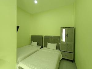 two beds in a small room with a window at Pudan Residence Parapat By Helocus in Parapat