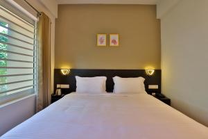 um quarto com uma grande cama branca e 2 almofadas em IVY RESIDENCY em Trivandrum