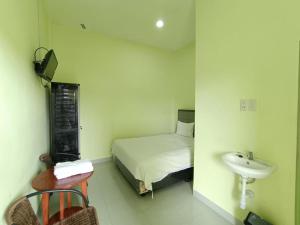 a small bedroom with a bed and a sink at Pudan Residence Parapat By Helocus in Parapat