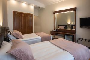 イスタンブールにあるヴァルダル パレス ホテル スペシャルカテゴリーのベッド2台と鏡が備わるホテルルームです。
