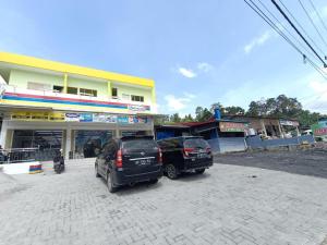 two cars parked in a parking lot in front of a building at Pudan Residence Parapat By Helocus in Parapat