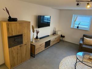 ein Wohnzimmer mit einem TV und einem hölzernen Entertainment-Center in der Unterkunft Ferienwohnung Hereinspaziert in Wilhelmshaven