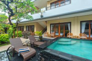 a swimming pool in front of a house at Liliy Guest House Kuta - Badung in Legian