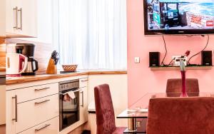 a kitchen with a table and a tv on the wall at Central Apartments Vienna - CAV in Vienna