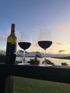 due bicchieri di vino seduti su un cornicione con una bottiglia di vino di The Sounds a Murdunna