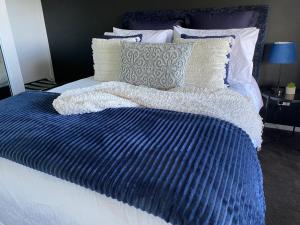 a bed with a blue and white blanket and pillows at The Sounds in Murdunna