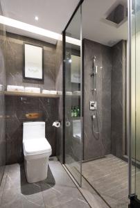 a bathroom with a toilet and a glass shower stall at Morning Hotel, Changsha Yanghu New City Metro Station in Changsha