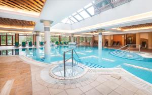 a large pool in a hotel with a large building at Aquarell Hotel in Cegléd