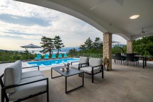 une terrasse avec des chaises, une table et une piscine dans l'établissement Villa Gloria, à Šilo