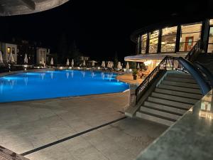 a large blue swimming pool with stairs next to a building at Quiet apartment with big terrace in Santa Marina with parking in Sozopol