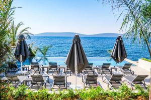 a pool with chairs and umbrellas and the ocean at İsolina Bodrum in Bodrum City