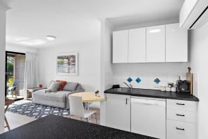 a kitchen with white cabinets and a living room at Sun Drenched Unit in Noosaville in Noosaville