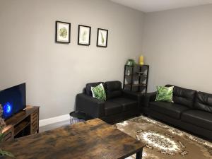 a living room with a black couch and a table at Executive or Large Family 5-bed House - Hosted by Hutch Lifestyle in Parkside