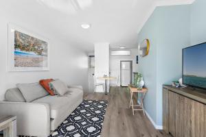 a living room with a couch and a flat screen tv at Sun Drenched Unit in Noosaville in Noosaville