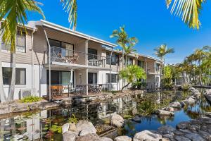 an exterior view of a resort with a pond and palm trees at Sun Drenched Unit in Noosaville in Noosaville