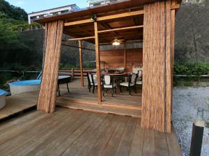 a wooden pergola with a table and chairs on a deck at Shirahama Meiji Villa in Shirahama
