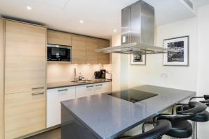 uma cozinha com um balcão preto e armários de madeira em Luxury modern 2BD flat in centre em Londres