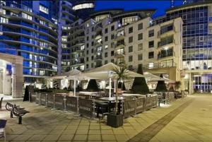 a patio with tables and umbrellas in front of buildings at Luxury modern 2BD flat in centre in London