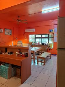 a kitchen with orange walls and a table and benches at 蘇馬利萬巒民宿 in Wanluan