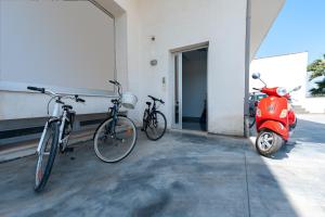 twee fietsen en een scooter geparkeerd naast een gebouw bij Solebarocco del sud - trilocale in Vernole